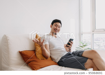 Happy man use smartphone in the living room for advertising content. Happy man use smartphone in the living room for advertising content. 95068691