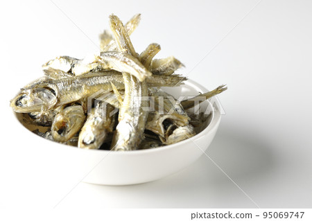 A small plate of boiled dried sardines is photographed against a white background. 95069747