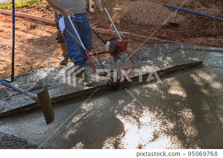 The machine is used to align the compacted layer of fresh concrete on a new driveway that has been constructed. 95069768
