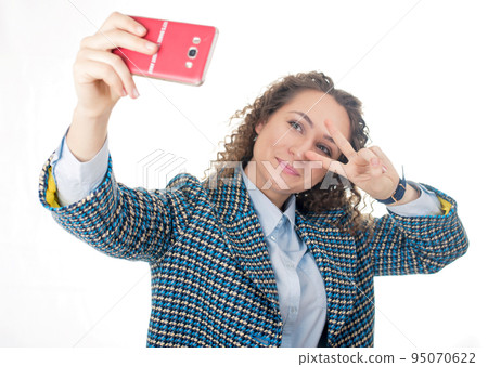 of a cute lovely woman taking selfie and showing peace sign with fingers over white background of a cute lovely woman taking selfie and showing peace sign with fingers over white background 95070622