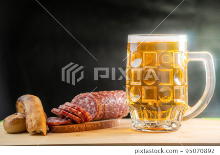 Pouring beer into the glass. Sausage with mug cold craft beer in a glass with water drops. Pint of Beer 95070892