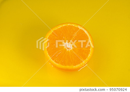 Water falling from orange hue orange on yellow background. Orange slice and water splashing, drops of juice falling from juicy fruit. Making cocktail of fruits, drinking cold lemonade Water falling from orange hue orange on yellow background. Orange slice and water splashing, drops of juice falling from juicy fruit. Making cocktail of fruits, drinking cold lemonade 95070924