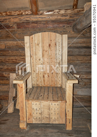 Medieval torture chair. The ancient armchair for tortures. Old wooden chair with spikes for torture 95070941