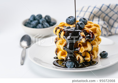 Pouring chocolate syrup on stack of fresh delicious homemade waffles. Pouring chocolate syrup on stack of fresh delicious homemade waffles. 95072008