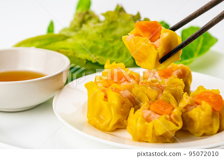 Using chopsticks picking up a fresh delicious homemade shrimp, minced pork and salted egg yolk steamed dumplings. Using chopsticks picking up a fresh delicious homemade shrimp, minced pork and salted egg yolk steamed dumplings. 95072010