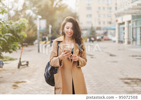 Lifestyle portrait pretty Asian kazakh woman with phone on street 95072508