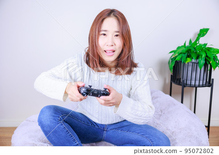 Japanese woman enjoying video games indoors 95072802