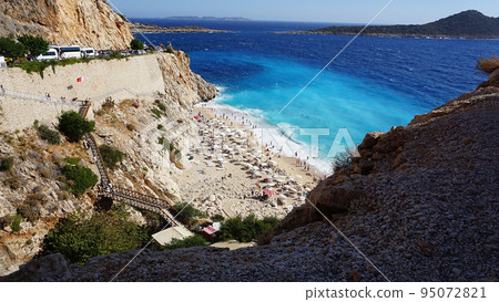 Aerial view from road of people crowd relaxing on beach. Swimming people in sea. Top view of Kaputas Beach between Kas and Kalkan at Turkey Aerial view from road of people crowd relaxing on beach. Swimming people in sea. Top view of Kaputas Beach between Kas and Kalkan at Turkey 95072821