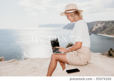 Digital nomad, Business woman working on laptop by the sea. Pretty lady typing on computer by the sea at sunset, makes a business transaction online from a distance. Freelance, remote work on vacation Digital nomad, Business woman working on laptop by the sea. Pretty lady typing on computer by the sea at sunset, makes a business transaction online from a distance. Freelance, remote work on vacation 95074268
