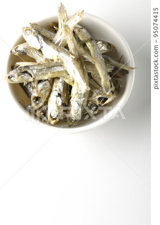 A bird's-eye view of dried sardines served on a small plate against a white background A bird's-eye view of dried sardines served on a small plate against a white background 95074415