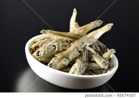 在黑色背景下拍攝了一小盤煮熟的干沙丁魚。 95074507