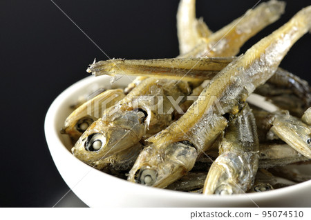 在黑色背景下拍攝了一小盤煮熟的干沙丁魚。 95074510