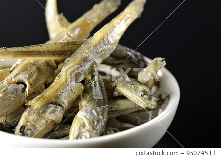 在黑色背景下拍攝了一小盤煮熟的干沙丁魚。 95074511