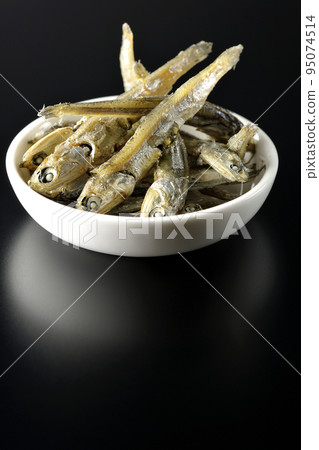在黑色背景下拍攝了一小盤煮熟的干沙丁魚。 95074514