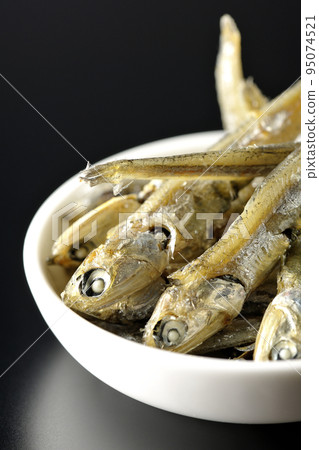 在黑色背景下拍攝了一小盤煮熟的干沙丁魚。 在黑色背景下拍攝了一小盤煮熟的干沙丁魚。 95074521