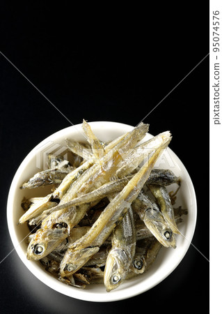 A bird's-eye view of dried sardines served on a small plate with a black background 95074576
