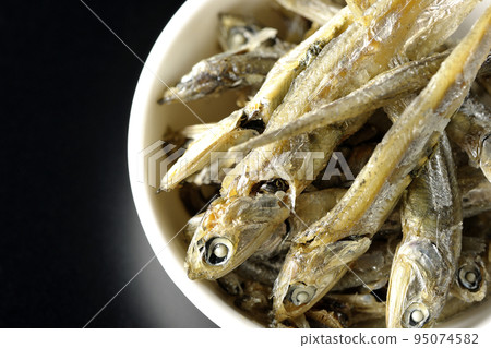 A bird's-eye view of dried sardines served on a small plate with a black background A bird's-eye view of dried sardines served on a small plate with a black background 95074582
