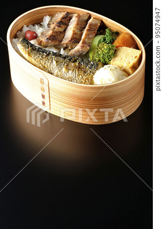 A grilled fish bento box containing pork, potato salad, omelet, etc. is photographed against a black background. A grilled fish bento box containing pork, potato salad, omelet, etc. is photographed against a black background. 95074947