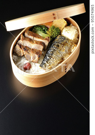 A grilled fish bento box containing pork, potato salad, omelet, etc. is photographed against a black background. A grilled fish bento box containing pork, potato salad, omelet, etc. is photographed against a black background. 95074965