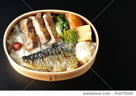 A bird's-eye view of a grilled fish bento box containing pork, potato salad, omelet, etc. in a black background 95075084