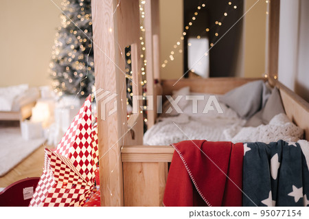 Children room with Christmas decorations. Presents in red festive packaging. Interior design for kids. Background of christmas tree lights 95077154