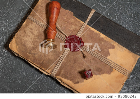 Antique shabby book tied with a thread with a wax seal and a stamp. The concept of secret knowledge Antique shabby book tied with a thread with a wax seal and a stamp. The concept of secret knowledge 95080242