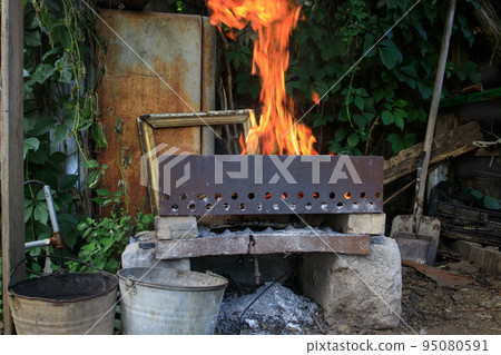 a fire in an old brazier in a dump of things 95080591
