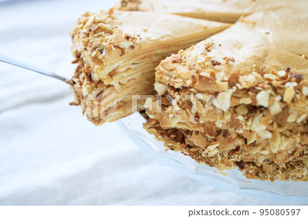 round napoleon cake, with caramel cream and a cut off piece, on a white background. copy space 95080597