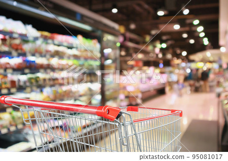 supermarket grocery store with fruit and vegetable shelves interior defocused background with empty red shopping cart 95081017