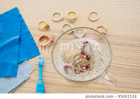 cleaning jewelry diamond ring with glass of hot water and dishwashing liquid on wood table background 95081538