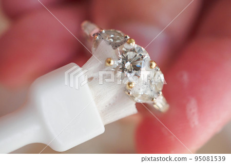 Jeweller hand cleaning and polishing vintage jewelry diamond ring closeup macro Jeweller hand cleaning and polishing vintage jewelry diamond ring closeup macro 95081539