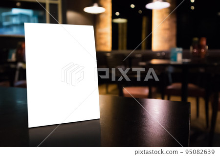 Mockup white label menu frame on table with cafe restaurant interior background 95082639