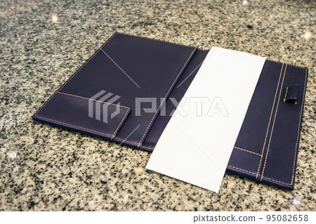 Blank empty white paper in restaurant payment billing receipt folder on granite table 95082658