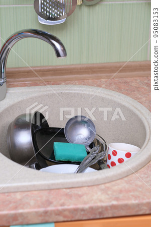 dirty dishes and kitchen utensils in a sink. messy kitchen. cluttered sink. daily routine, chores and housekeeping. vertical dirty dishes and kitchen utensils in a sink. messy kitchen. cluttered sink. daily routine, chores and housekeeping. vertical 95083153