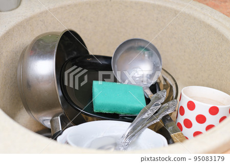 dirty dishes and kitchen utensils in a sink. messy kitchen. cluttered sink. daily routine, chores and housekeeping. close up 95083179
