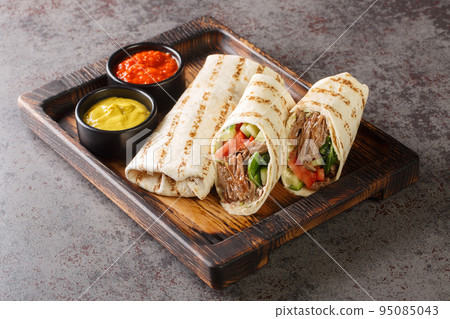 Shawarma sandwich gyro fresh roll of lavash closeup on the wooden board. Horizontal 95085043