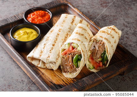 Arab Traditional Food Shawarma Rolled Sandwich with Sauce and vegetables closeup on the wooden board. Horizontal 95085044