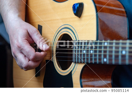 The musician plays the acoustic guitar. 95085114