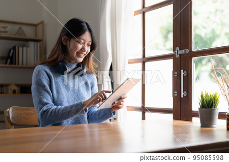 Happy young woman wearing headphone and using digital tablet at home. Happy young woman wearing headphone and using digital tablet at home. 95085598