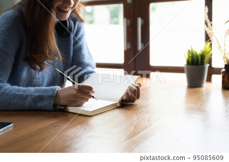 Close up of woman study online distant on laptop make note write in notebook sitting on desk at home. Smart female writer or student handwrite in stationery notepad, planning or making list. 95085609