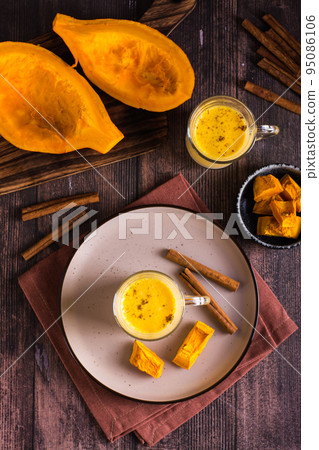 Autumn homemade pumpkin latte with cinnamon in glasses and pieces of pumpkin. Top and vertical view Autumn homemade pumpkin latte with cinnamon in glasses and pieces of pumpkin. Top and vertical view 95086106