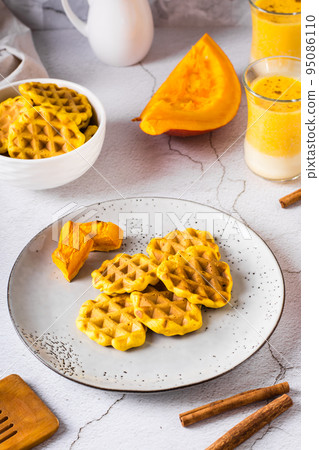Belgian homemade pumpkin waffles on a plate on the table. Autumn baking. Vertical view Belgian homemade pumpkin waffles on a plate on the table. Autumn baking. Vertical view 95086110
