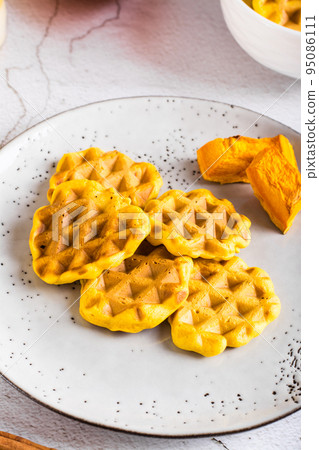 Homemade belgian  pumpkin waffles on a plate on the table. Autumn baking. Closeup vertical view 95086111