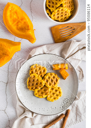 Belgian homemade pumpkin waffles on a plate on the table. Autumn baking. Top and vertical view Belgian homemade pumpkin waffles on a plate on the table. Autumn baking. Top and vertical view 95086114