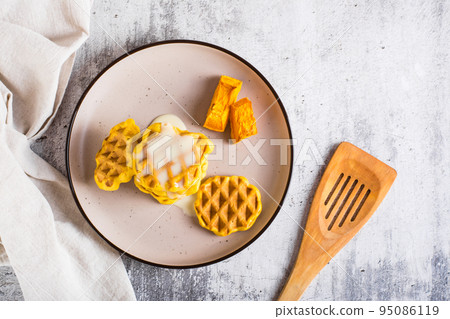 A stack of Belgian homemade pumpkin waffles topped with sweet sauce on a plate. Top view 95086119