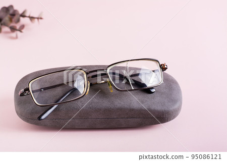Broken glasses on a hard case on a pink background. The concept of careful storage of optics 95086121