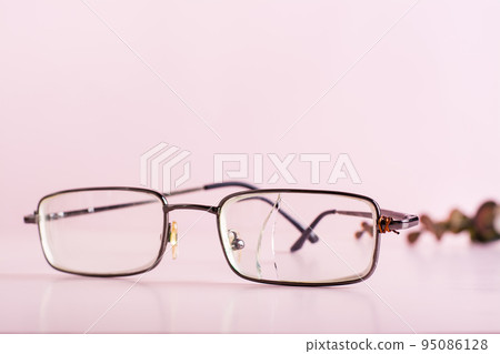 Old glasses with a broken lens and a wire attached to the shackle on a pink background Old glasses with a broken lens and a wire attached to the shackle on a pink background 95086128
