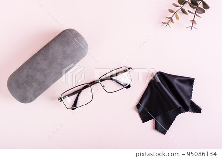 Glasses, case and cleaning cloth on a pink background. Storage and care. Top view. Glasses, case and cleaning cloth on a pink background. Storage and care. Top view. 95086134