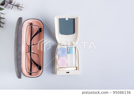 Glasses in a case and a set for contact lenses on a blue. Choice of vision correction method. Glasses in a case and a set for contact lenses on a blue. Choice of vision correction method. 95086136