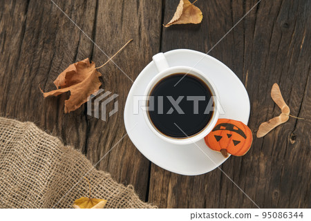 Cup of coffee or tea on brown wooden table. Halloween gingerbread in pumpkin shape Autumn. Top view Cup of coffee or tea on brown wooden table. Halloween gingerbread in pumpkin shape Autumn. Top view 95086344